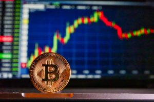 Moneta Bitcoin na tle ekranu z wykresem wartości kryptowaluty