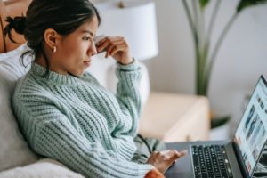 kobieta pracuje online trzyma laptopa na kolanach