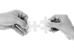 dwie dłonie łączące puzzle
